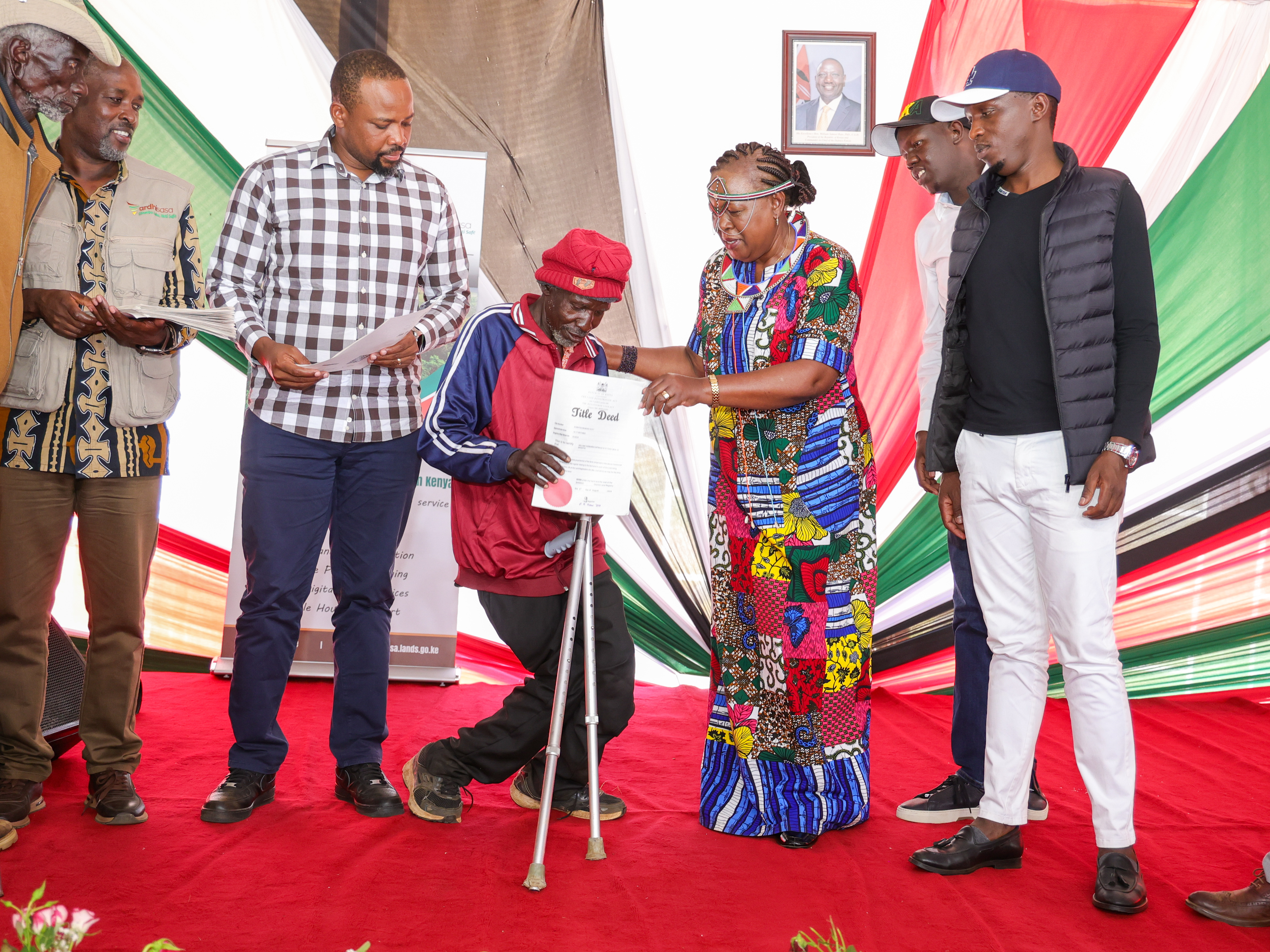 Cabinet Secretary Alice Wahome presents a title deed to a beneficiary